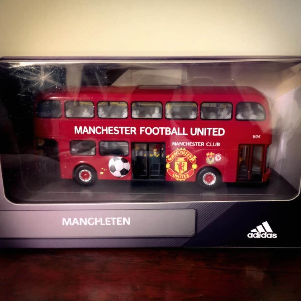 AI generated: Bus painted with Manchester United Football Club placed in a plastic case.