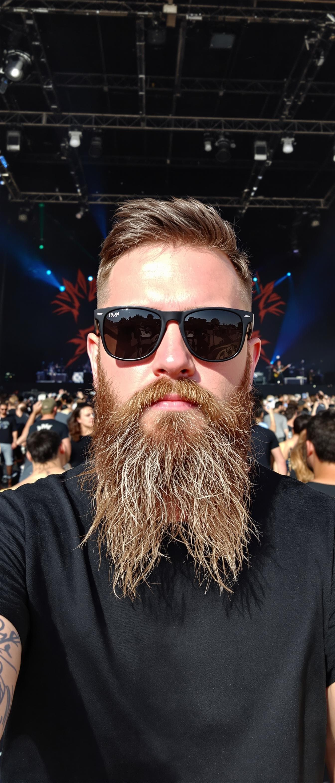 AI generated: A young Caucasian man with short brown hair, a long beard, wearing sunglasses and a black t-shirt, s...