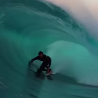 AI generated video: a video that switches every two seconds between different shots of a surfer riding a giant wave
