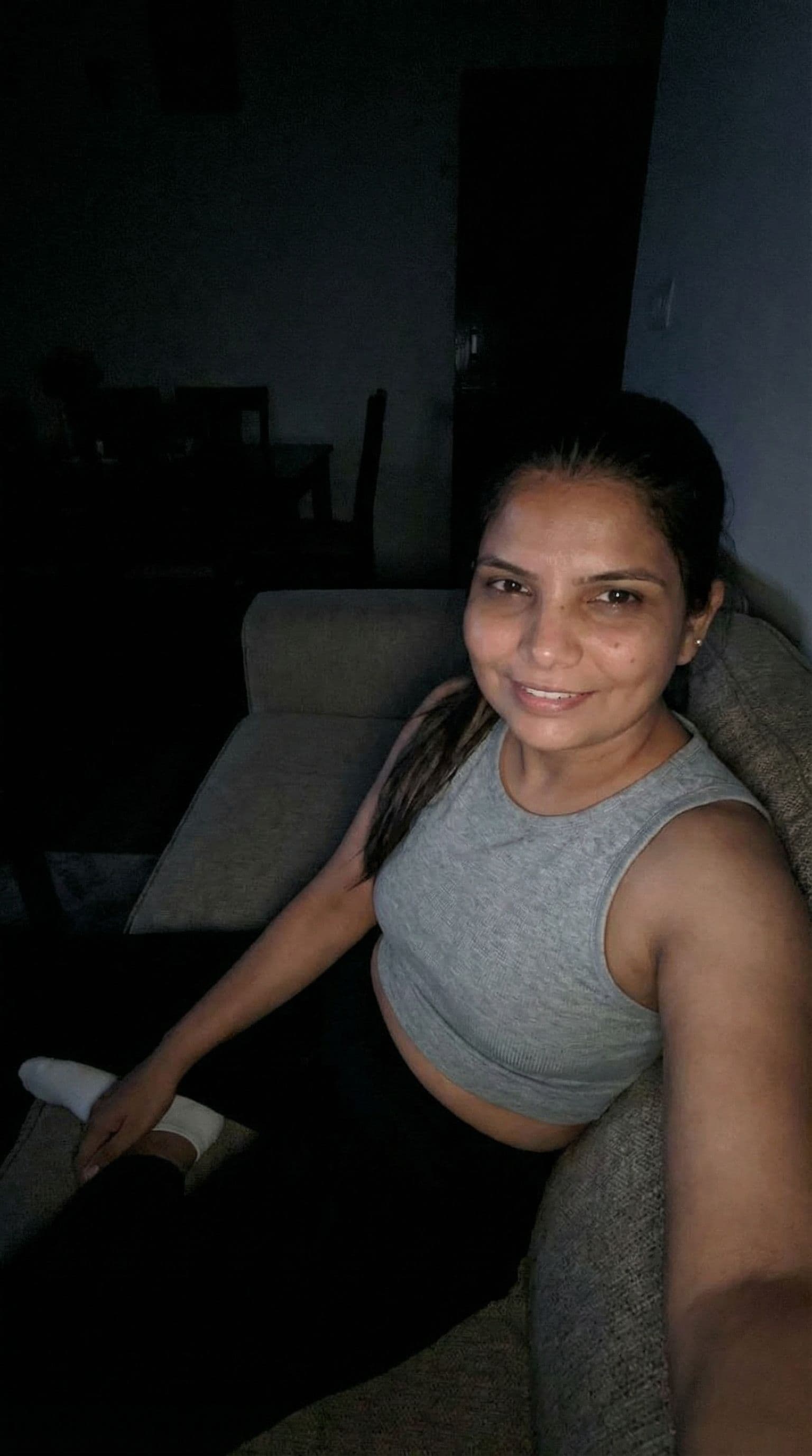 AI generated: Indian, Taking a selfie on a couch at night, no lights, wearing a cropped home tanktop and white soc...