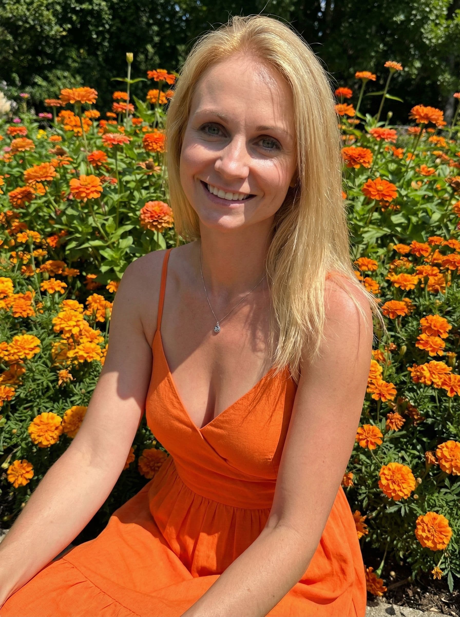 AI generated: beautiful fashion model with orange dress, and sitting on orange flowerbed, outside in the mid day s...
