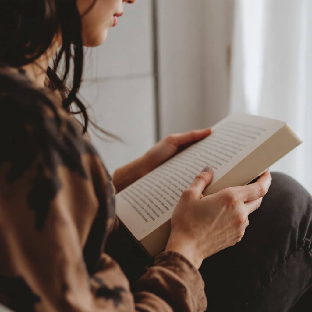 AI generated: a person holding a book and sitting side view

