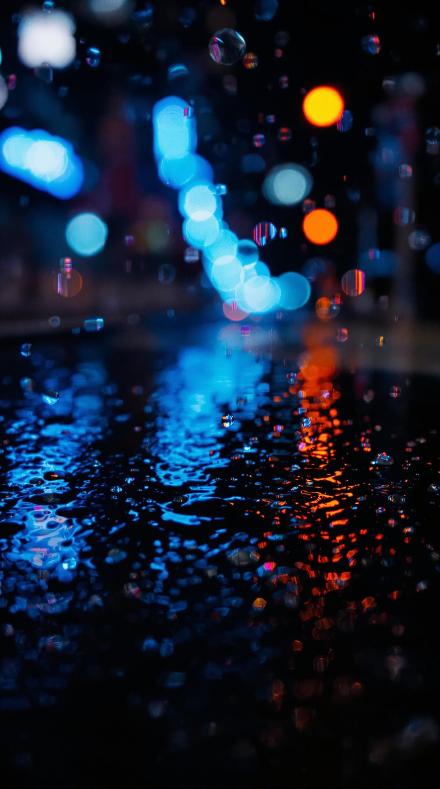 AI generated: Abstract image of raindrops on a wet dark surface reflecting blue and orange neon city lights