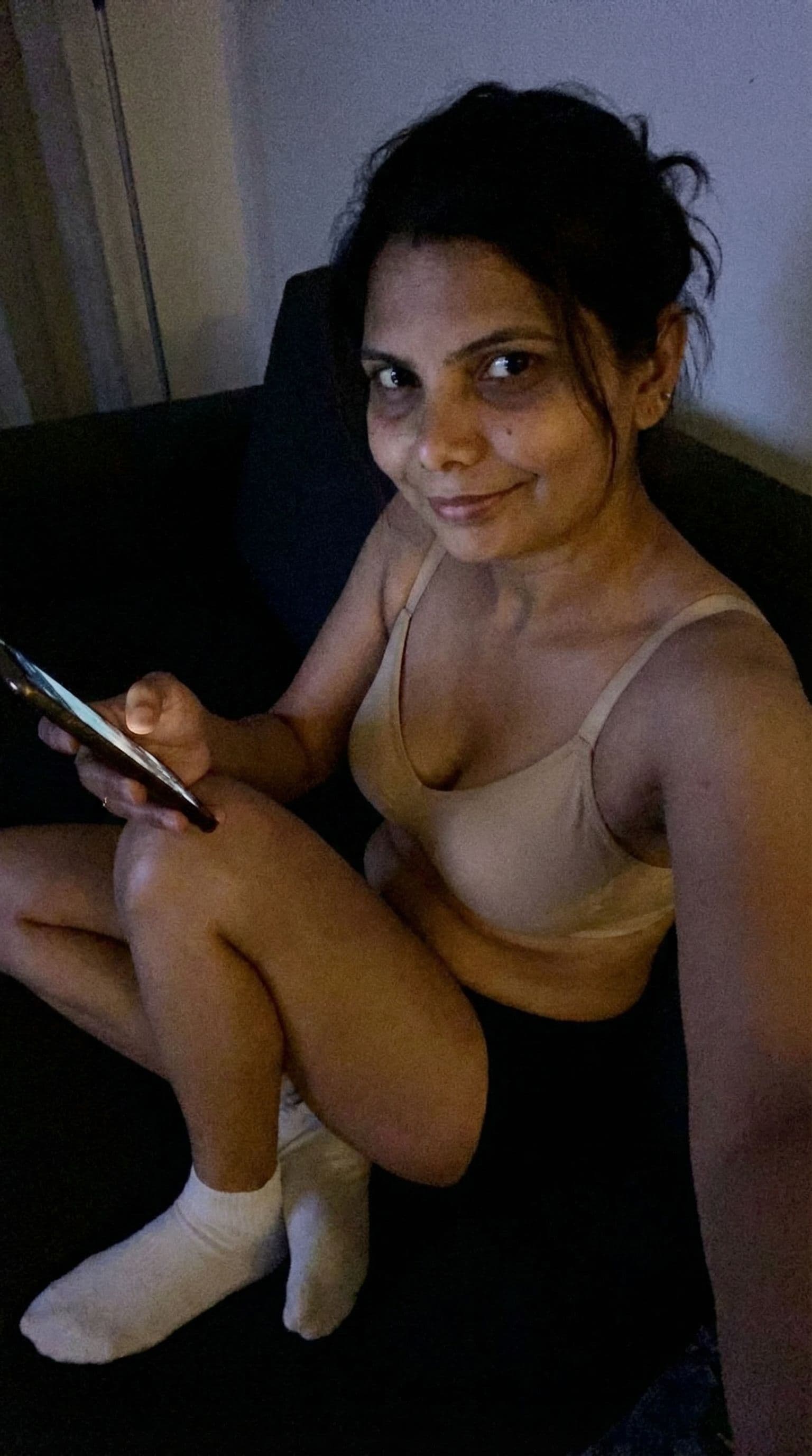 AI generated: Romantic selfie looking at me,a sloppy snapshot. Sitting on a couch at night teasing(no lights), hom...