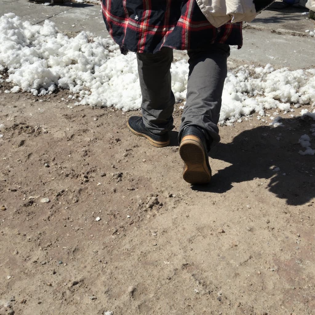 AI generated: Siguiendo las pisadas, que se vean solamente los pies de un hombre con pantalón y zapatos.

