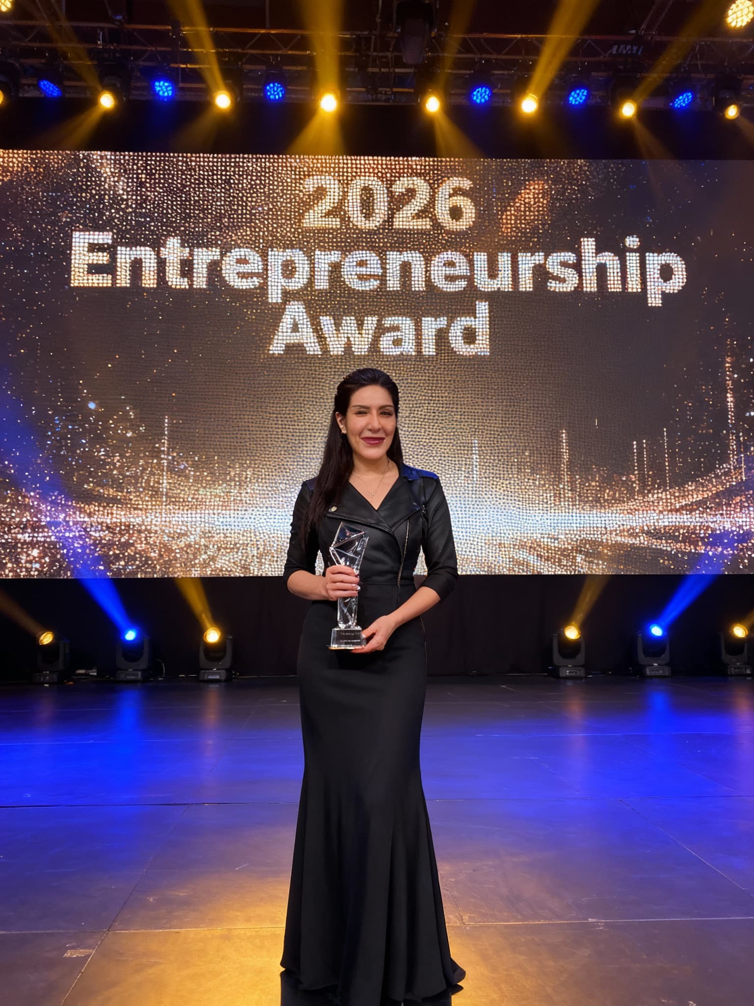 AI generated: “A confident and inspiring woman standing on stage at the 2026 Entrepreneurship Awards ceremony. She...