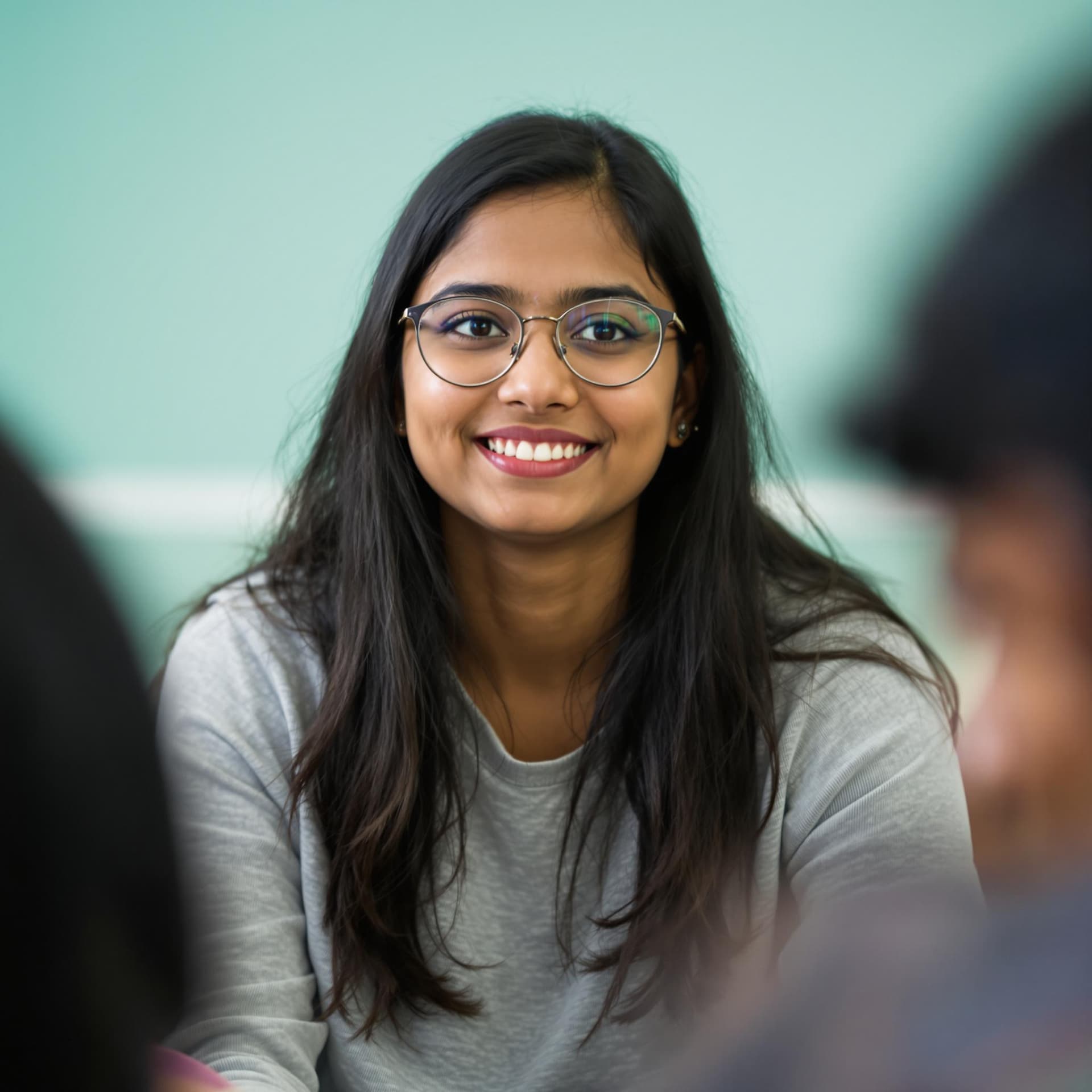 AI generated: The image features a young Indian woman with long, dark hair and glasses, sitting in a relaxed pose....