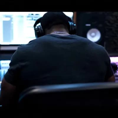 AI generated video: A cinematic back view of a  black musician sitting in a professional recording studio. The camera is...