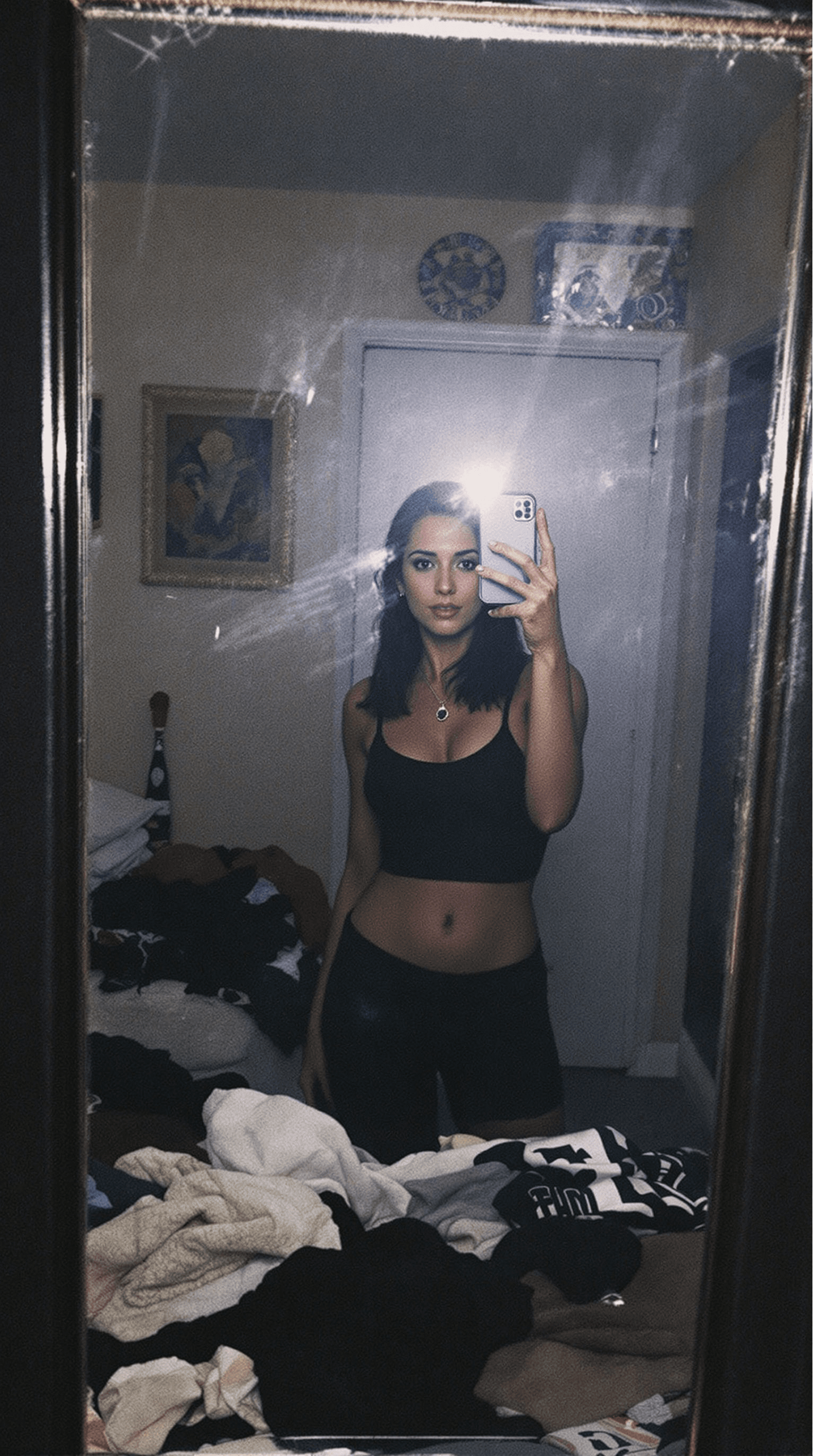 AI generated:  woman stands in front of a mirror, capturing a selfie. The image quality is grainy, with a slight b...