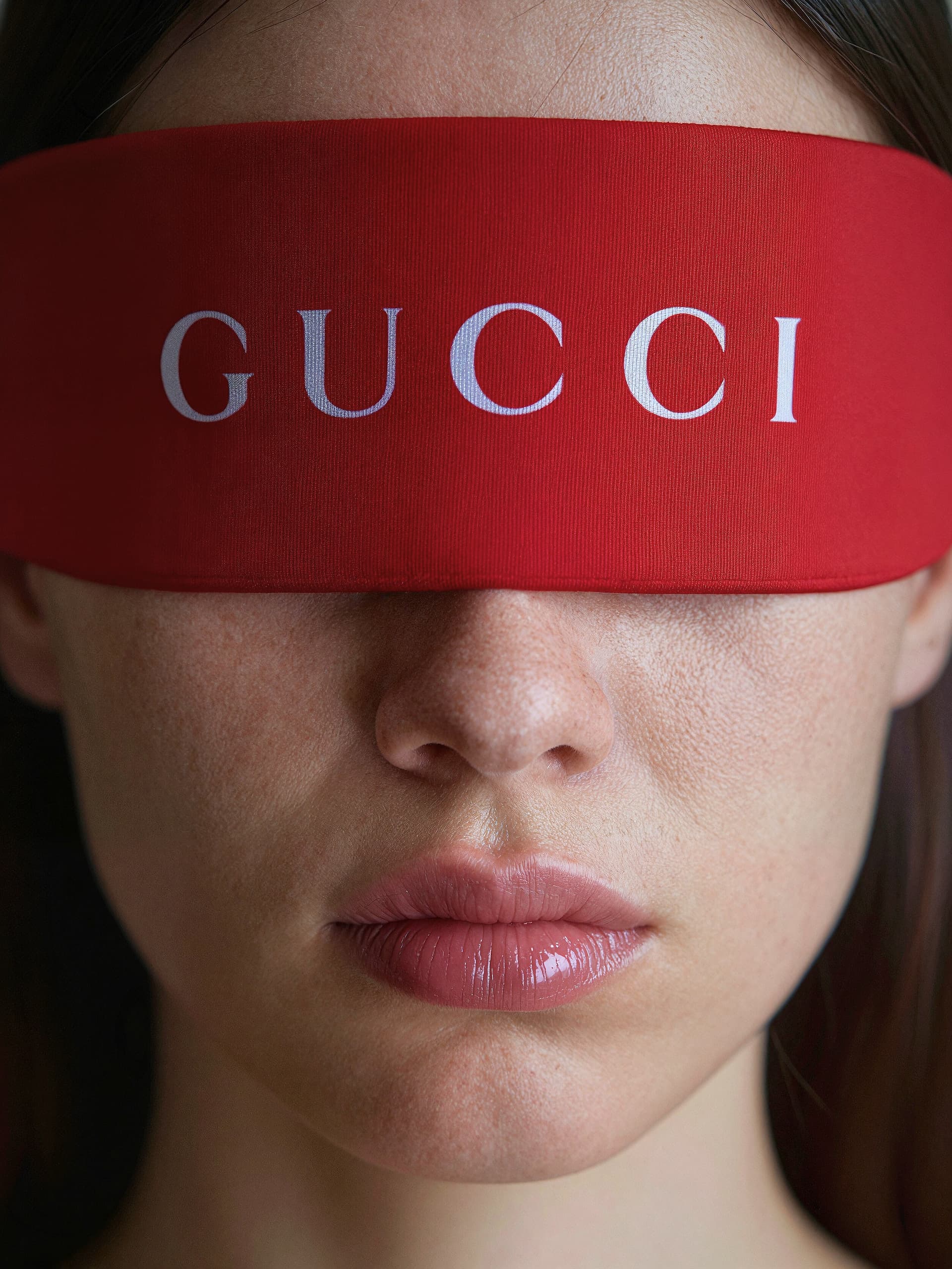 AI generated: A close-up portrait of a young individual with freckled skin, wearing a red Gucci blindfold and head...