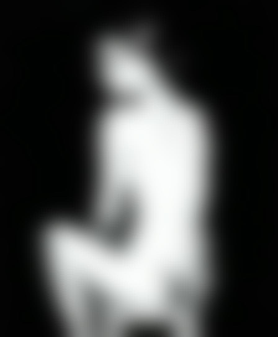 AI generated: Black an white photo of A woman sits confidently on a wooden stool, her bare back turned to us. Her ...