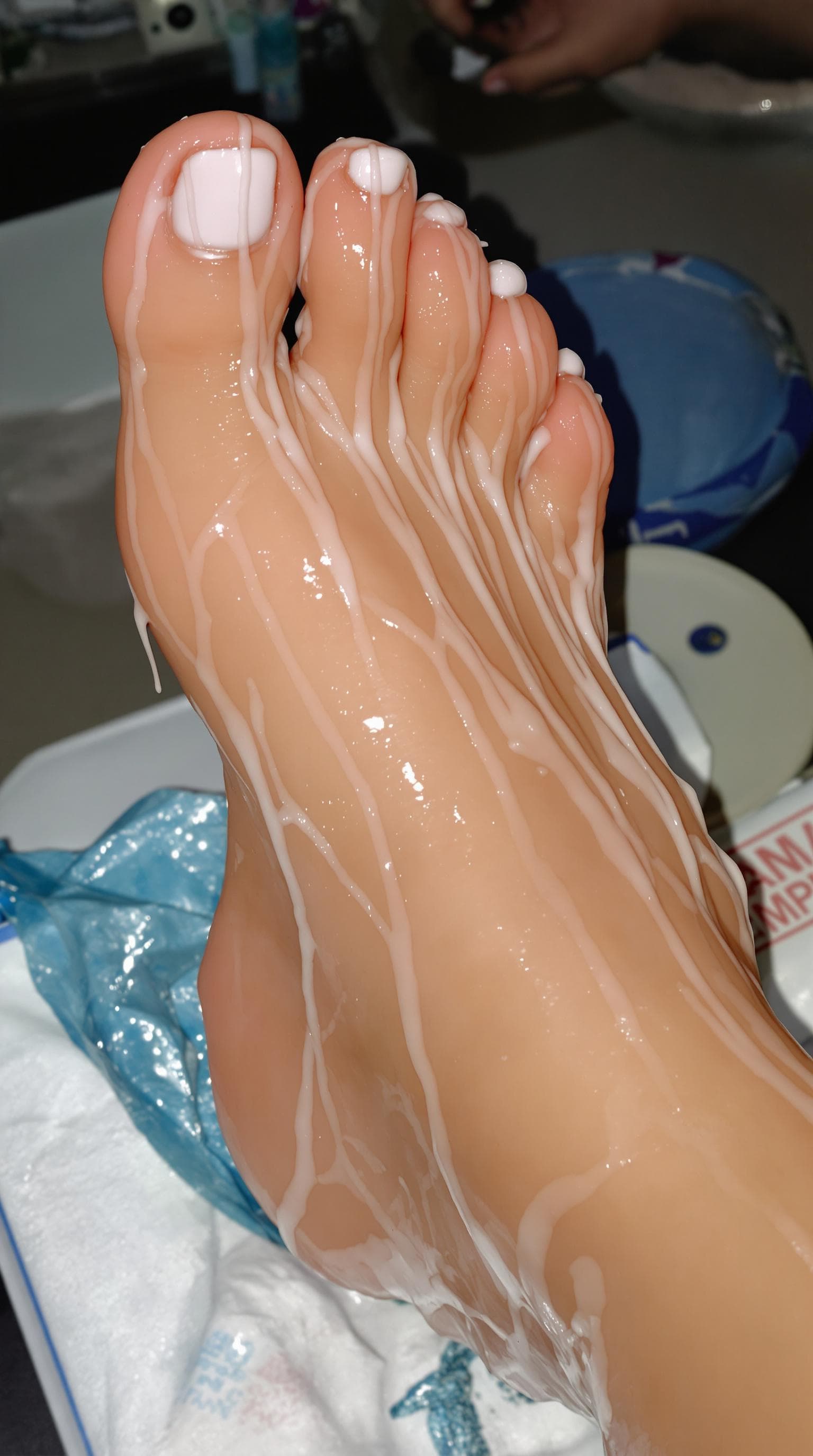 AI generated: Oiled dripping pedicured feet with white nail polish,, realistic, no deformed, complete feet