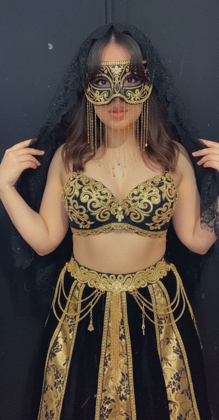 AI generated:   Adorned in an elaborate black and gold attire, The woman's attire consists of a black bra, a black...