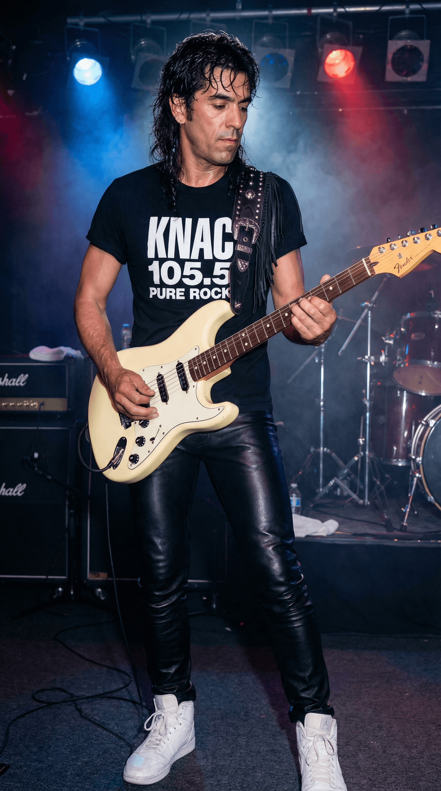 AI generated: Guitar player is standing on a nightclub stage wearing a black t-shirt with the white KNAC 105.5 PUR...