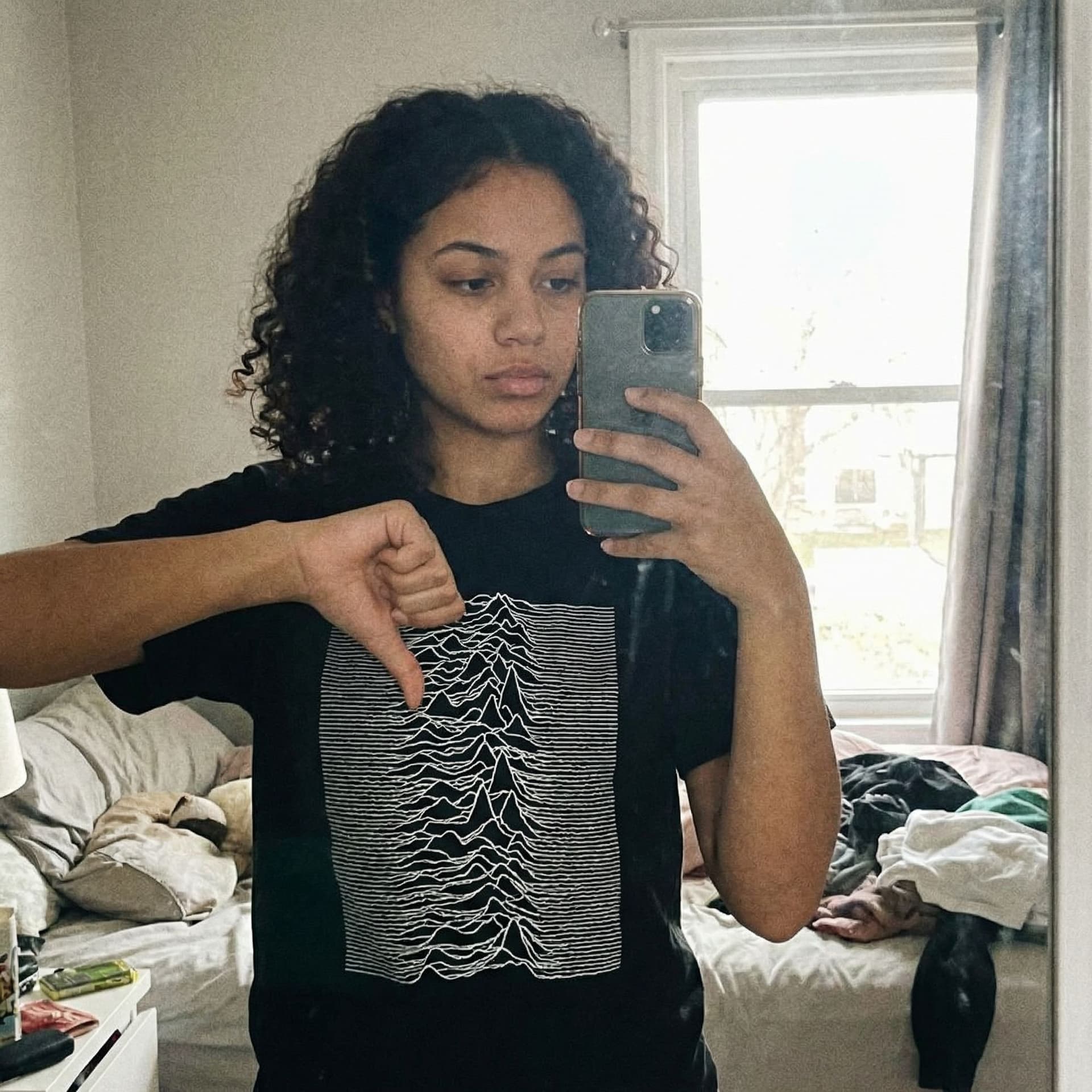 AI generated: A girl wearing a black t-shirt with a prominent, white chest takes a selfie, placing her hand on her...