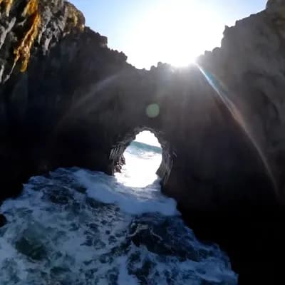 AI generated video: Camera slashes across jagged headlands at mast height, then snap-rolls into a helical dive through a...