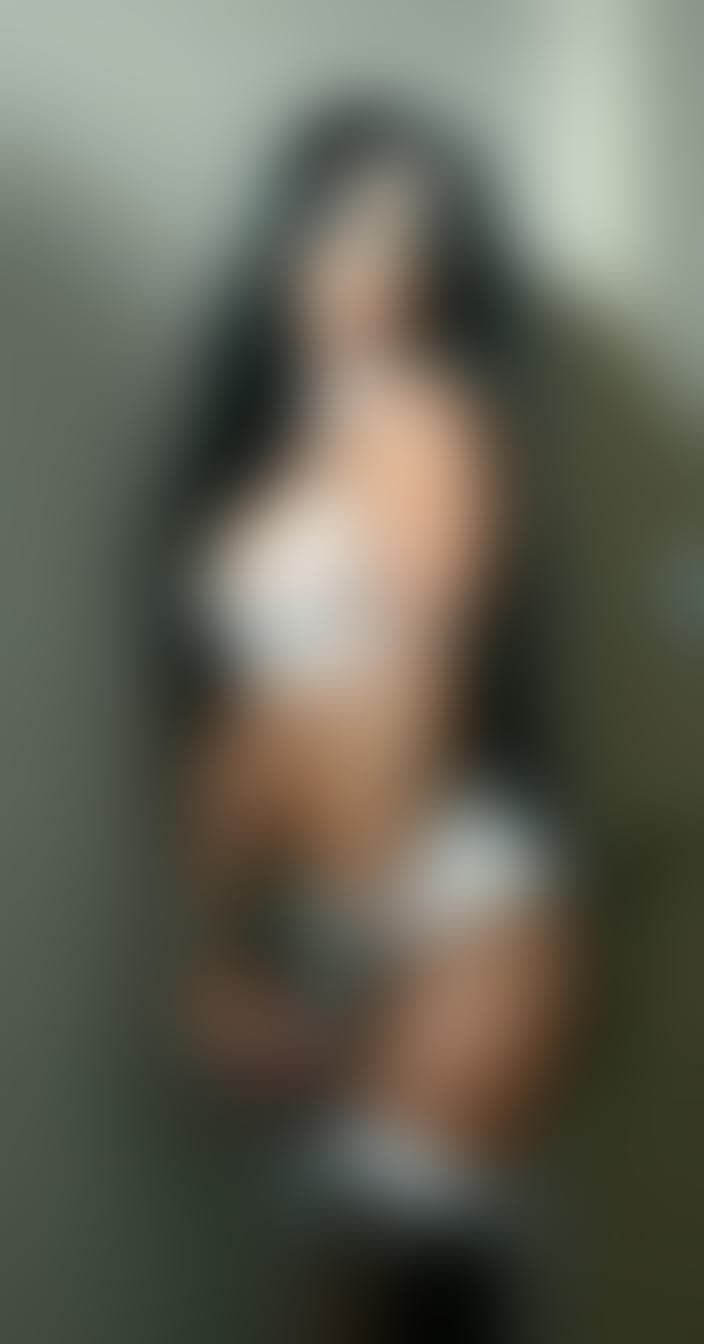 AI generated: A drag queen with long dark hair,wearing a white lace bra,garter belt,and thigh-high stockings,with ...