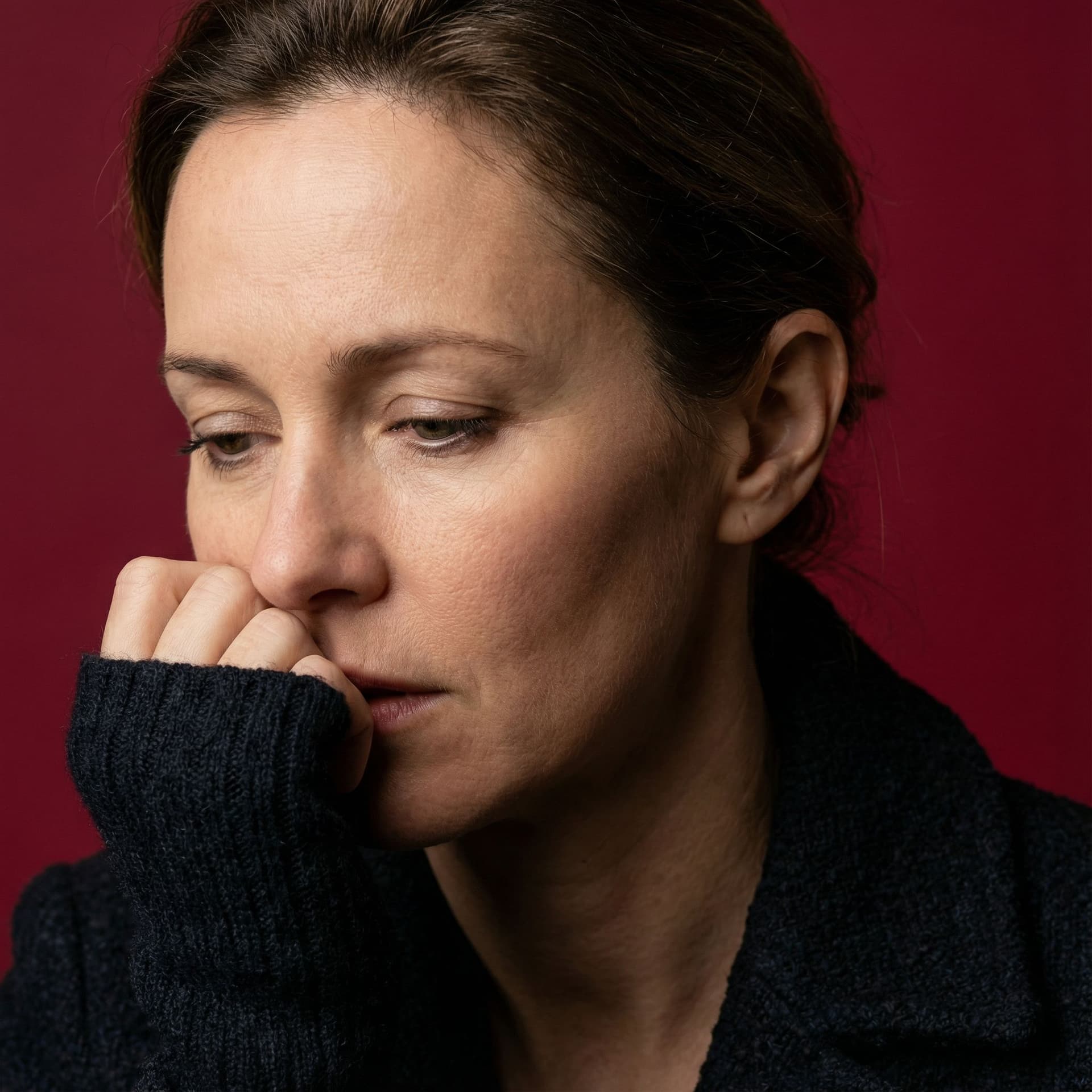 AI generated: image of a woman with a thoughtful expression, covering half of her face with her hand, pure red bac...