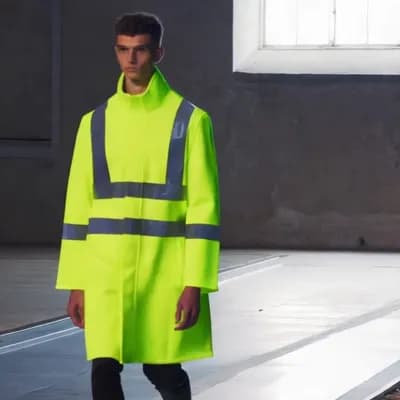 AI generated video: a male model walks down the catwalk wearing a yellow hi-vis safety vest 