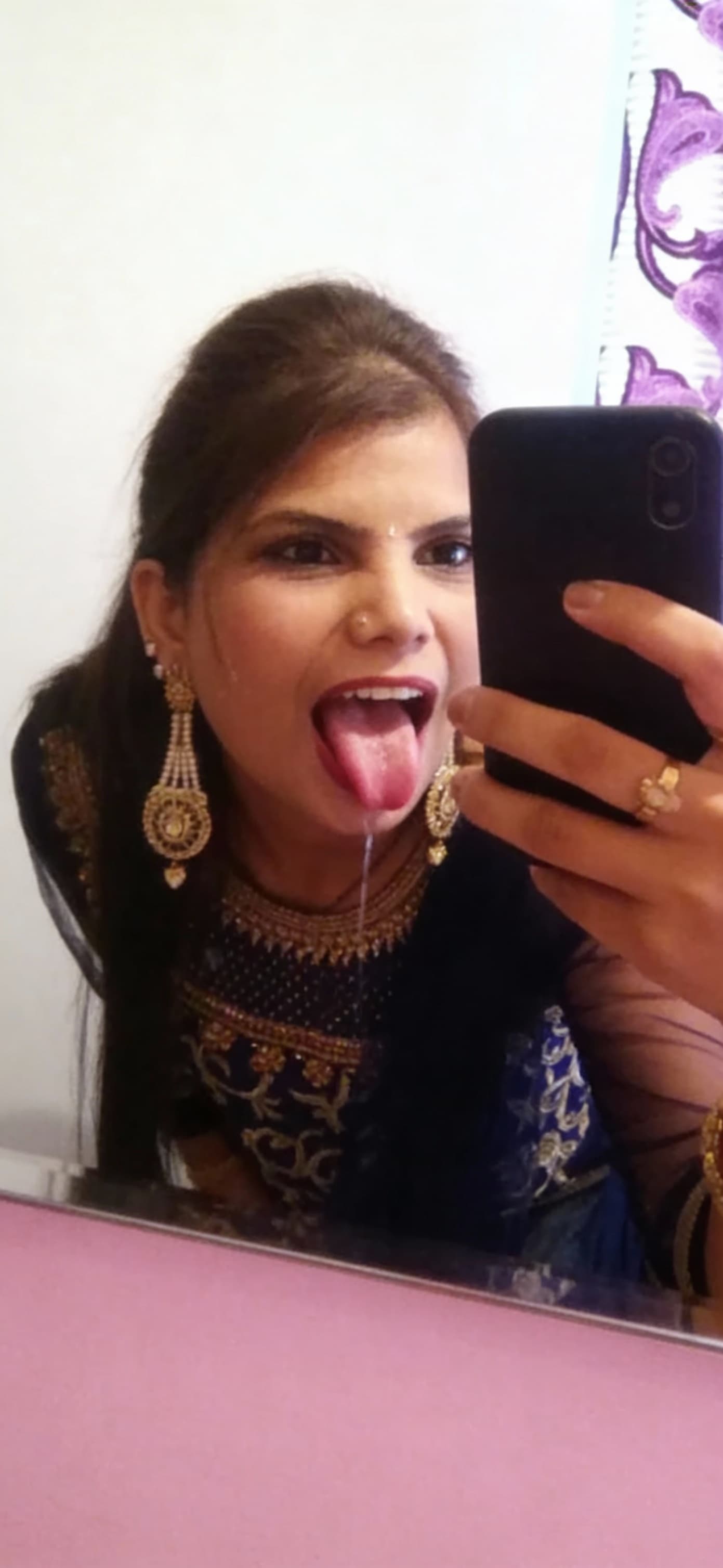 AI generated: Takes a mirror selfie while leaning over, sticking her tongue out with saliva, mouth wide open 