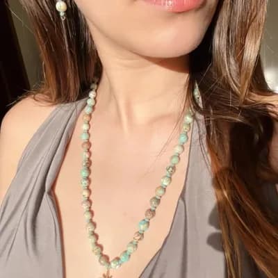AI generated video: Elegant close-up of a woman wearing a natural crystal necklace made of African turquoise jasper bead...