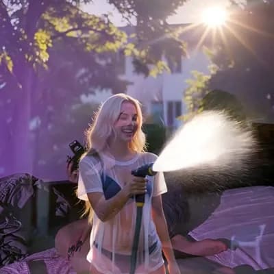 AI generated video:  laughing as she plays with a garden hose. She is wearing a soaked, translucent white t-shirt over a...