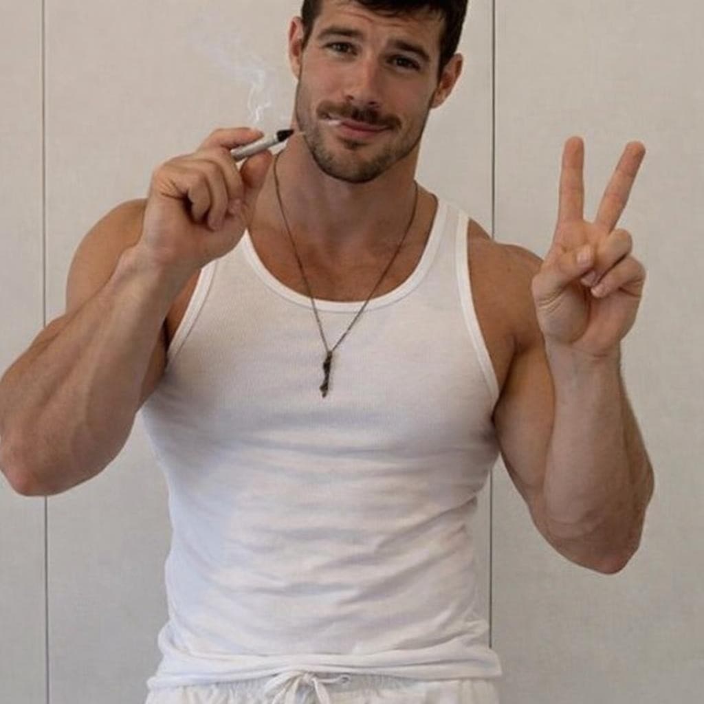 AI generated: make this man look just like the input image wearing a white tank top and white short shorts smoking...