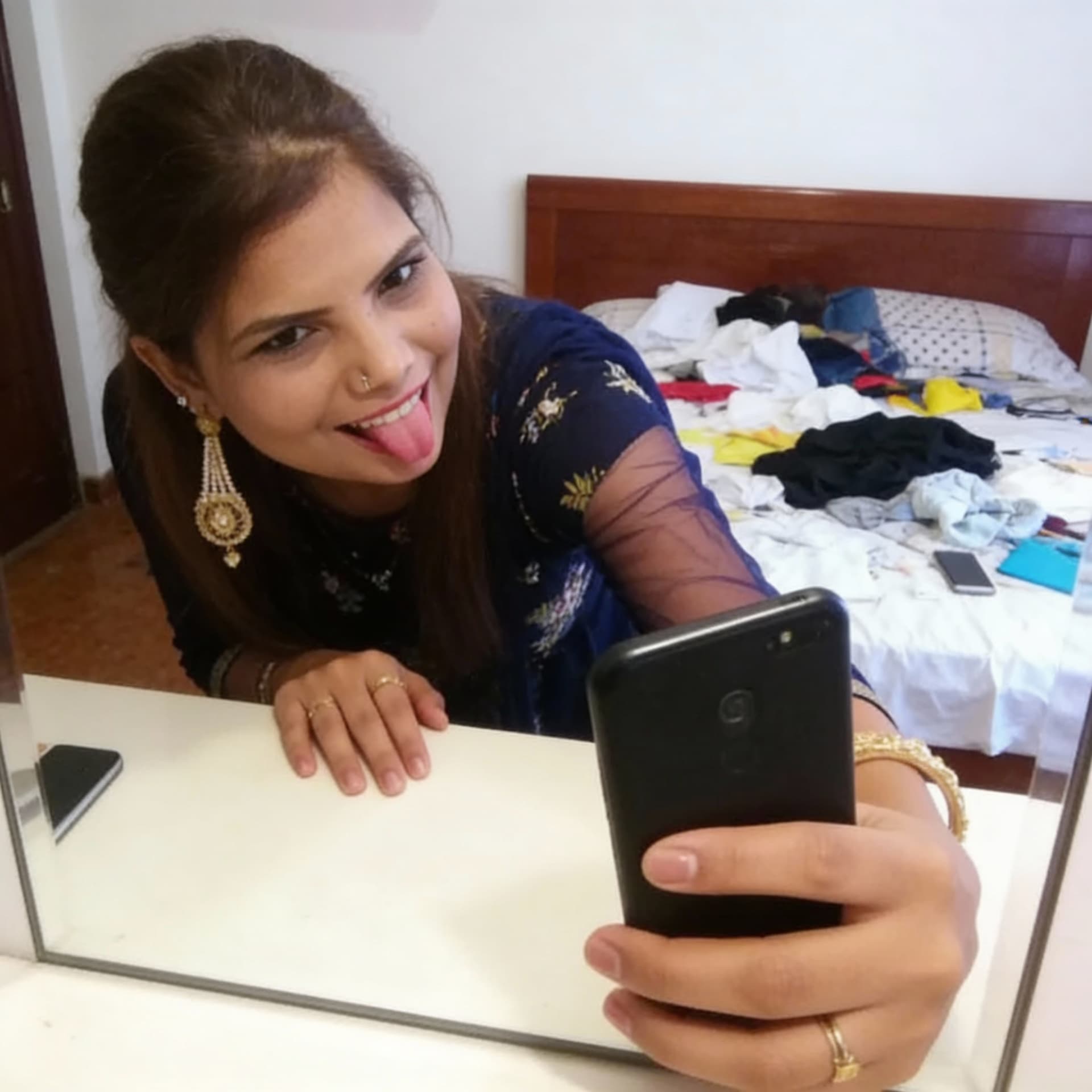 AI generated:  takes a mirror selfie in a messy bedroom.

The woman has her phone in one hand and she is using her...