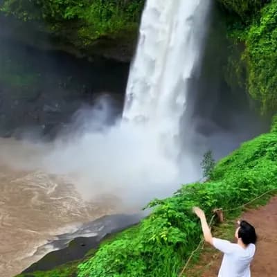 AI generated video: Waterfalls flow, rivers flow, boat slowly moves upstream, two people on the shore wave at the boat, ...