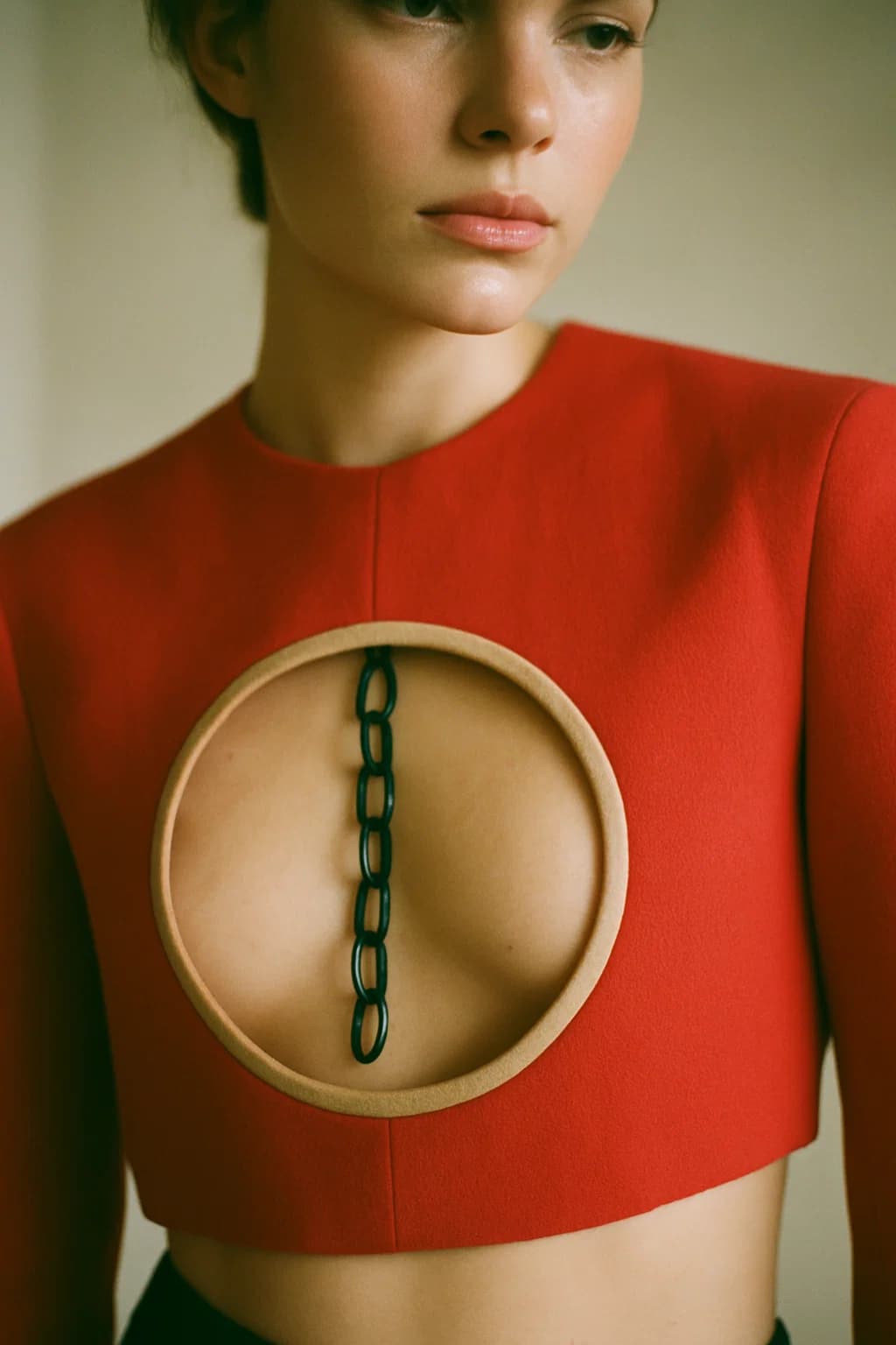 AI generated: Fashion editorial close-up. A model wears a bold, avant-garde garment: a structured red top with a l...