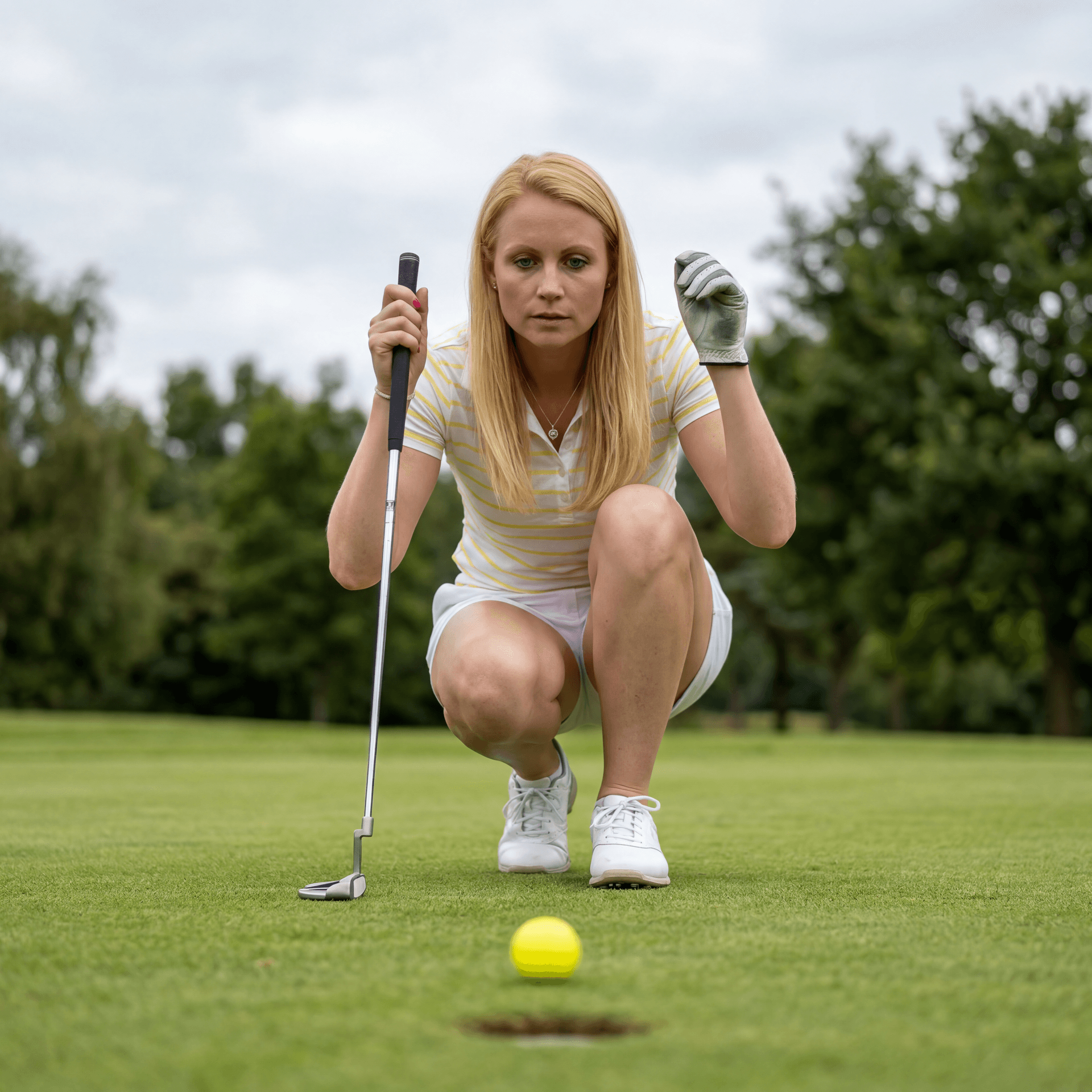 AI generated: A young, athletic woman with long blonde hair is in a low crouching pose on a golf course, about to ...