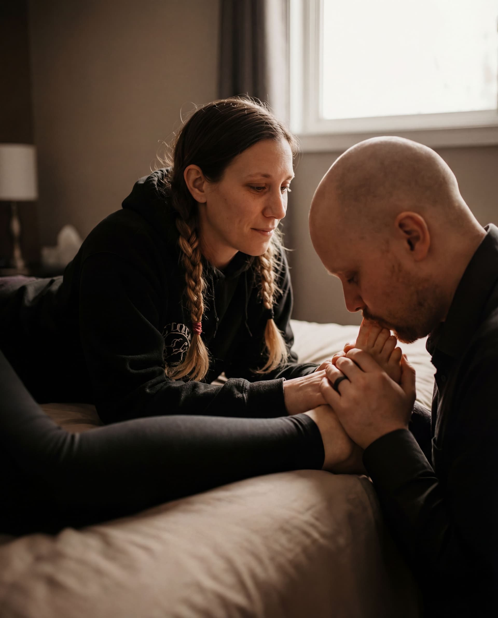 AI generated: A romantic, artistic scene of a couple — man gently kissing wife’s foot — in soft lighting, wife lay...