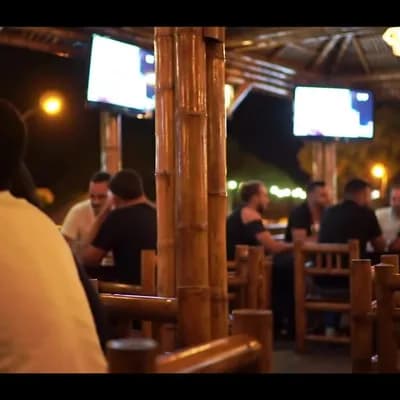 AI generated video: A tavern made of guadua, with wooden chairs and tables, decorated with two televisions, some streetl...