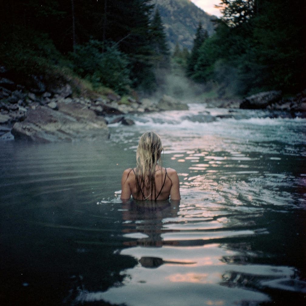 AI generated: hot spring in a river flow, steam rises from the water, a woman with long wet blonde hair swims in t...