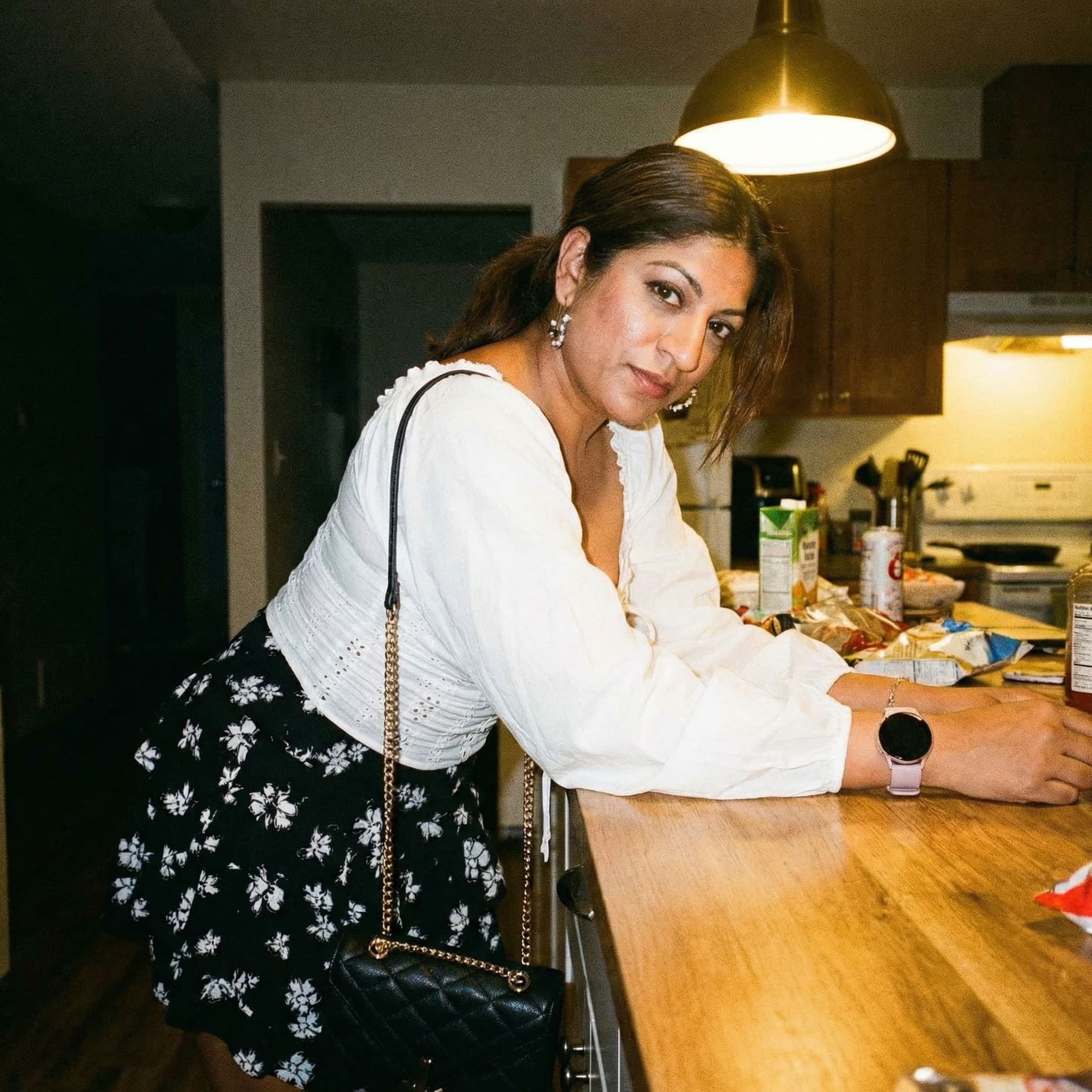 AI generated: Wearing same clothes, leans over a kitchen desk, close view, 35-year-old indian woman, busty body, a...