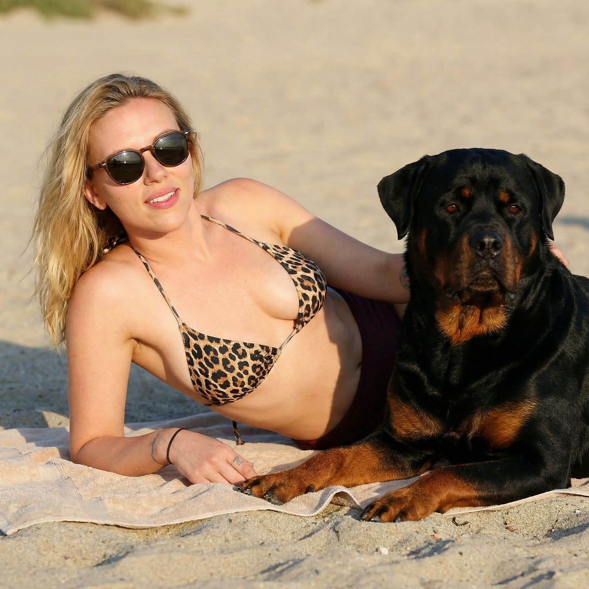 AI generated: Scarlett Johansson with leopard bikini at the beach, lying on side at the beach with her rottweiler,...