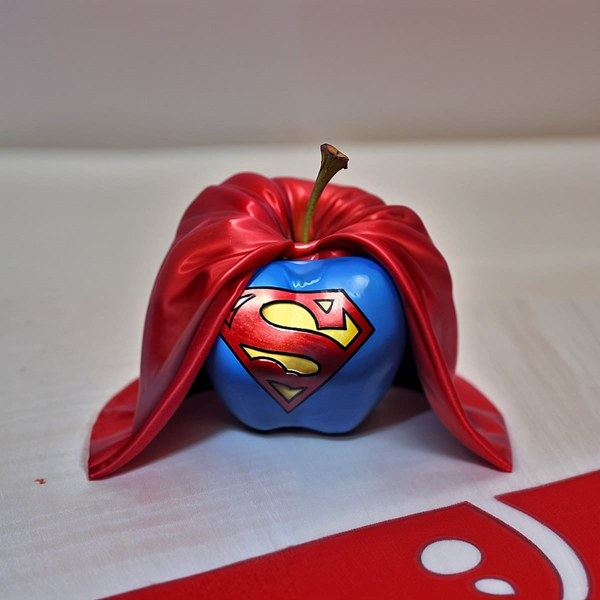 AI generated: (an apple fruit:1.12) with superman logo on it and red cloak