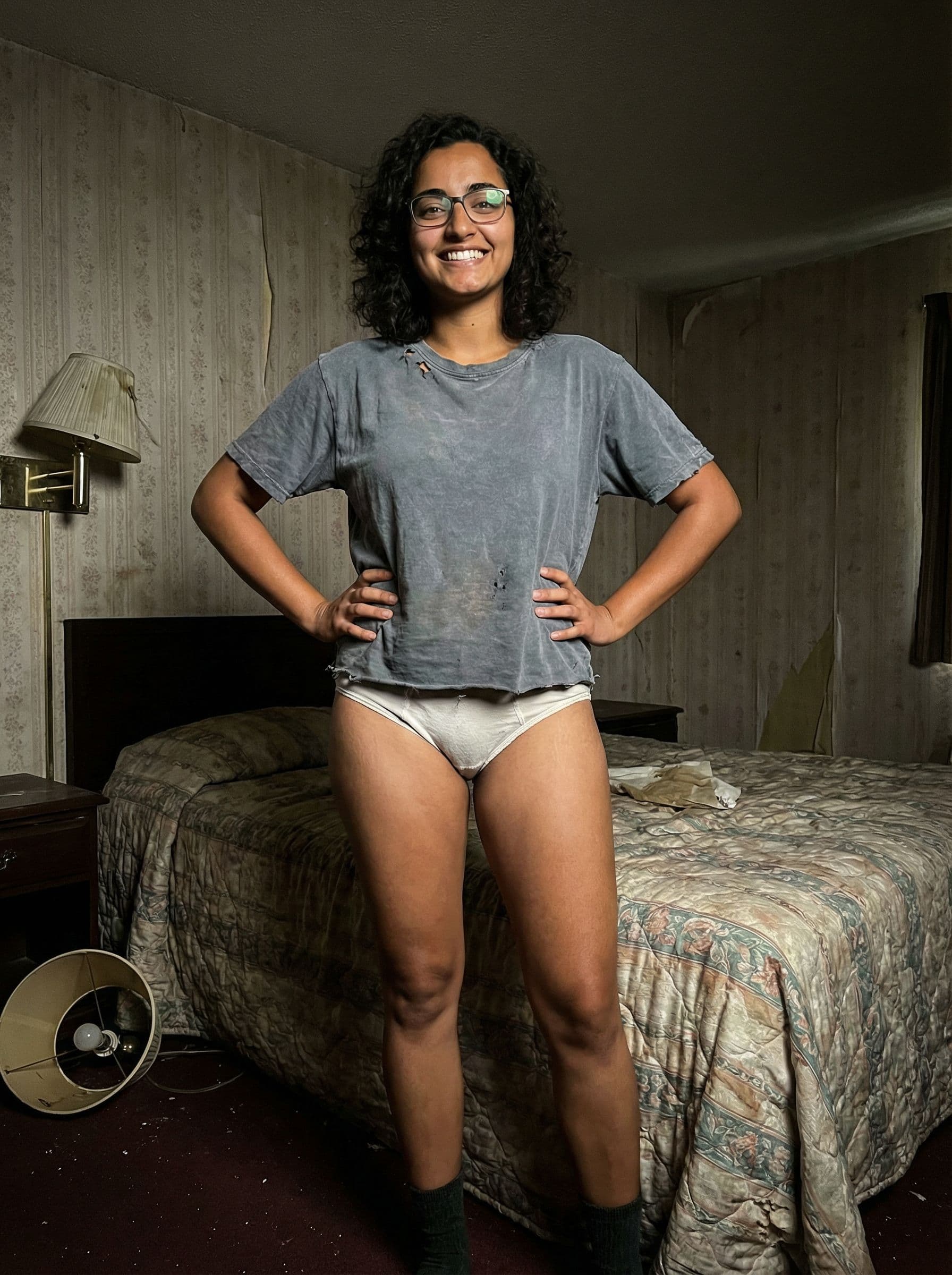 AI generated: In a very cheap looking motel room. One beautiful brunette girl with a tan and brown eyes is standin...