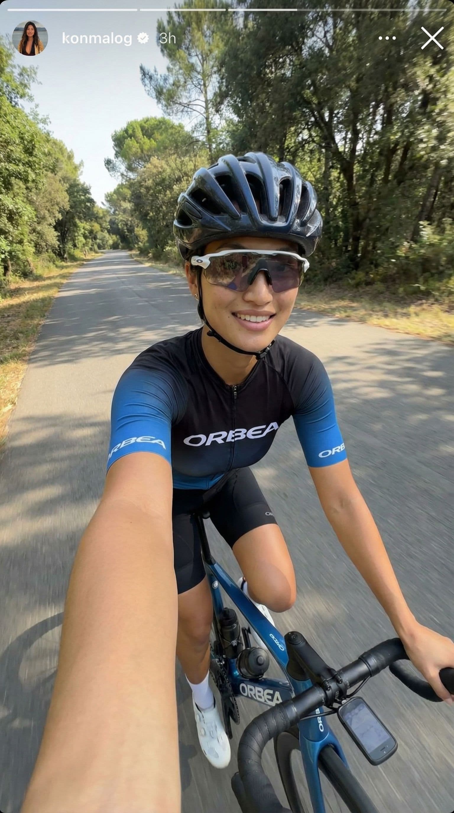 AI generated: A realistic iPhone-style selfie taken on a quiet road in daylight. The woman from the reference imag...