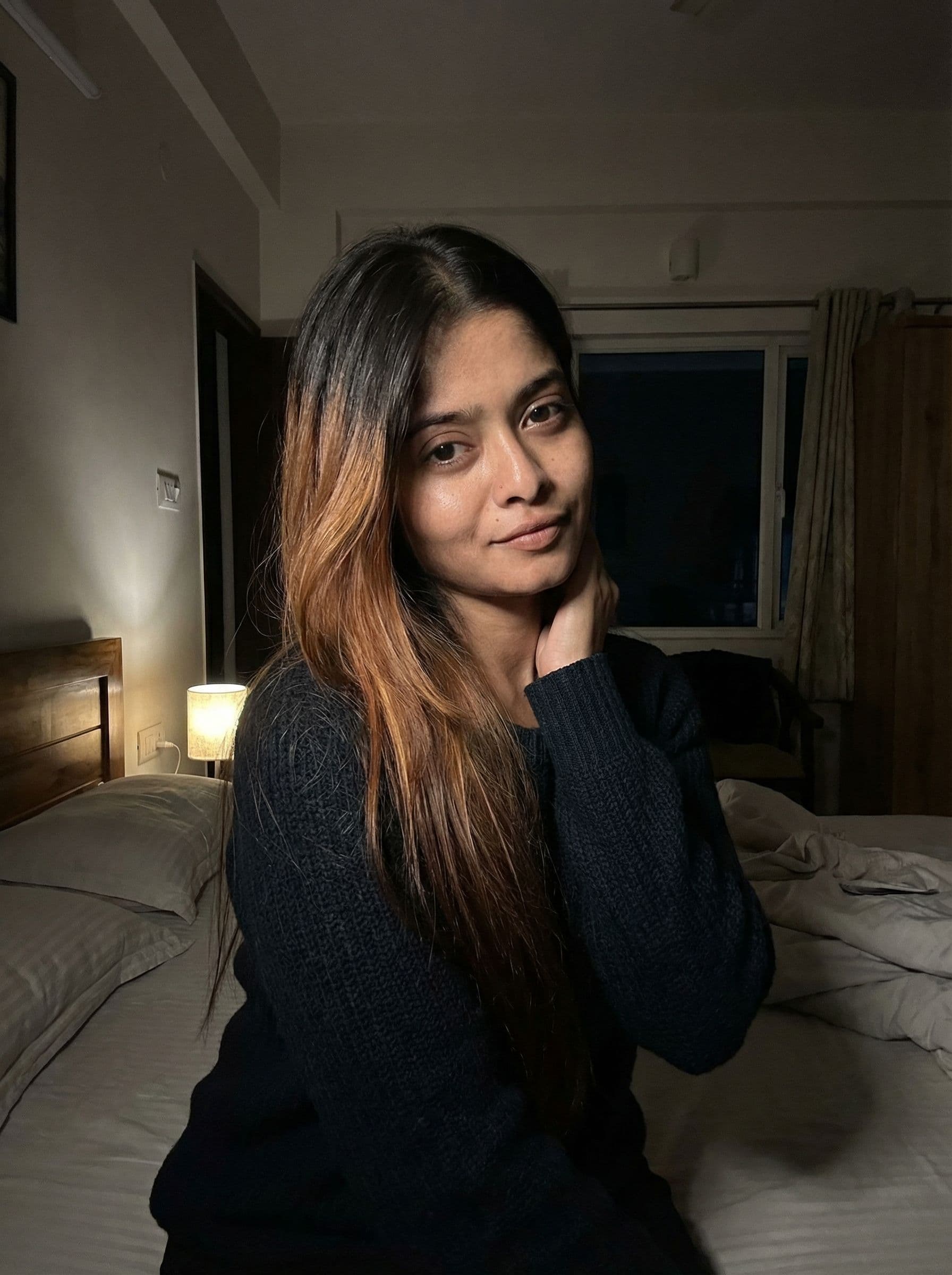 AI generated: tones sits on a bed in a dimly lit room. Her blonde with dark highlights