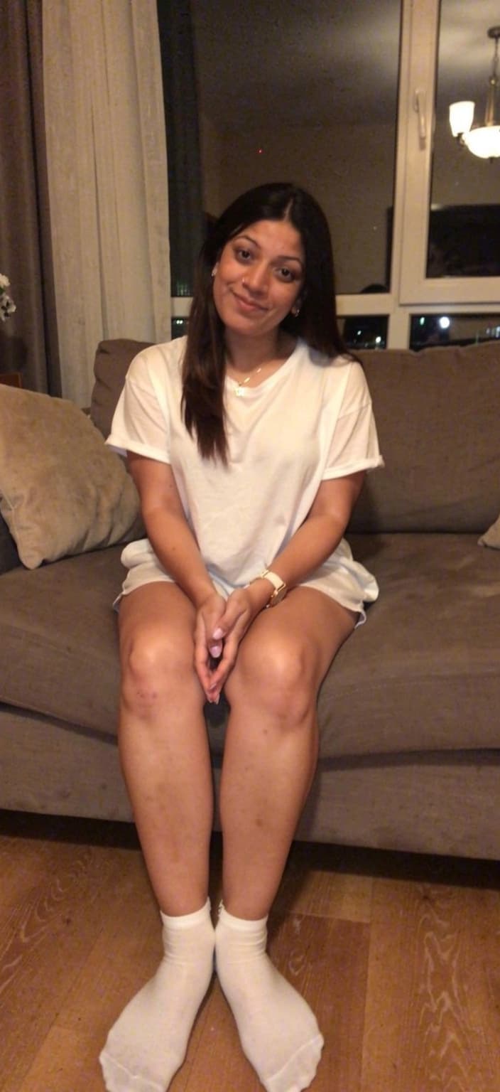 AI generated: looking at me,a sloppy snapshot. Sitting on a couch at night teasing, home bra and white socks