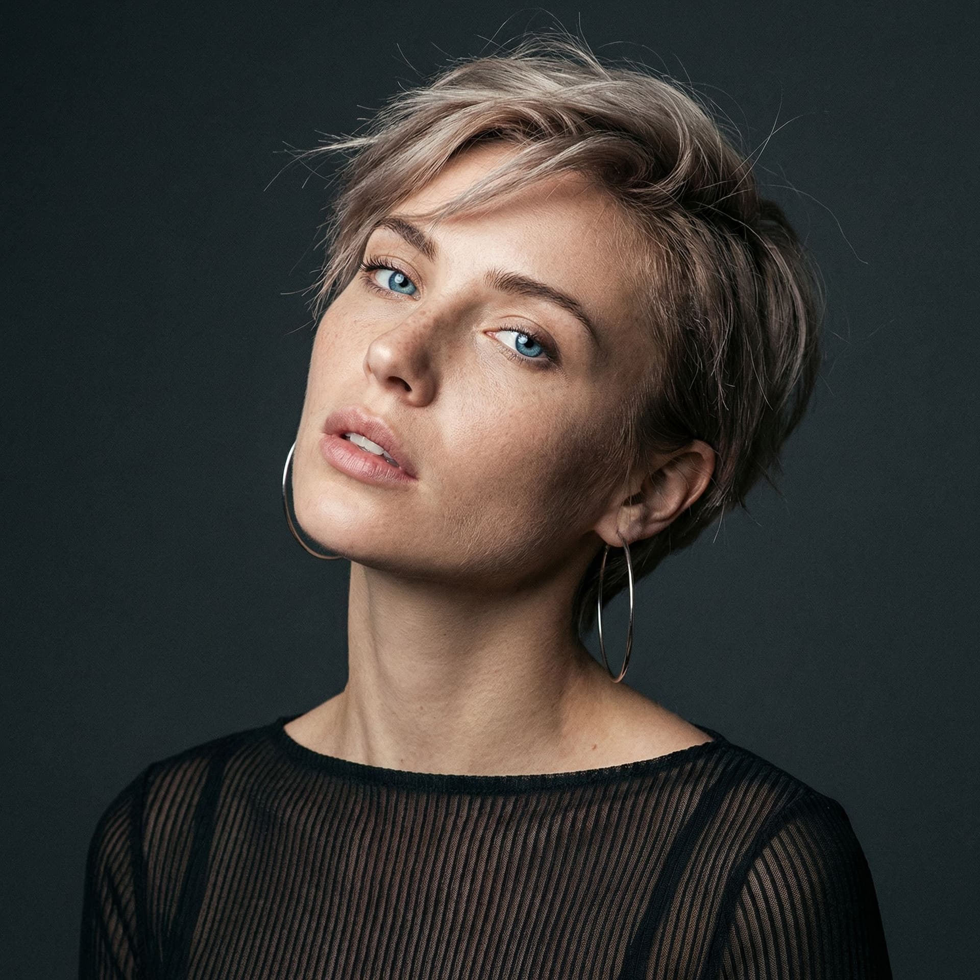 AI generated: hyper-realistic portrait of a stunning woman with a short messy platinum brown pixie cut, windblown ...