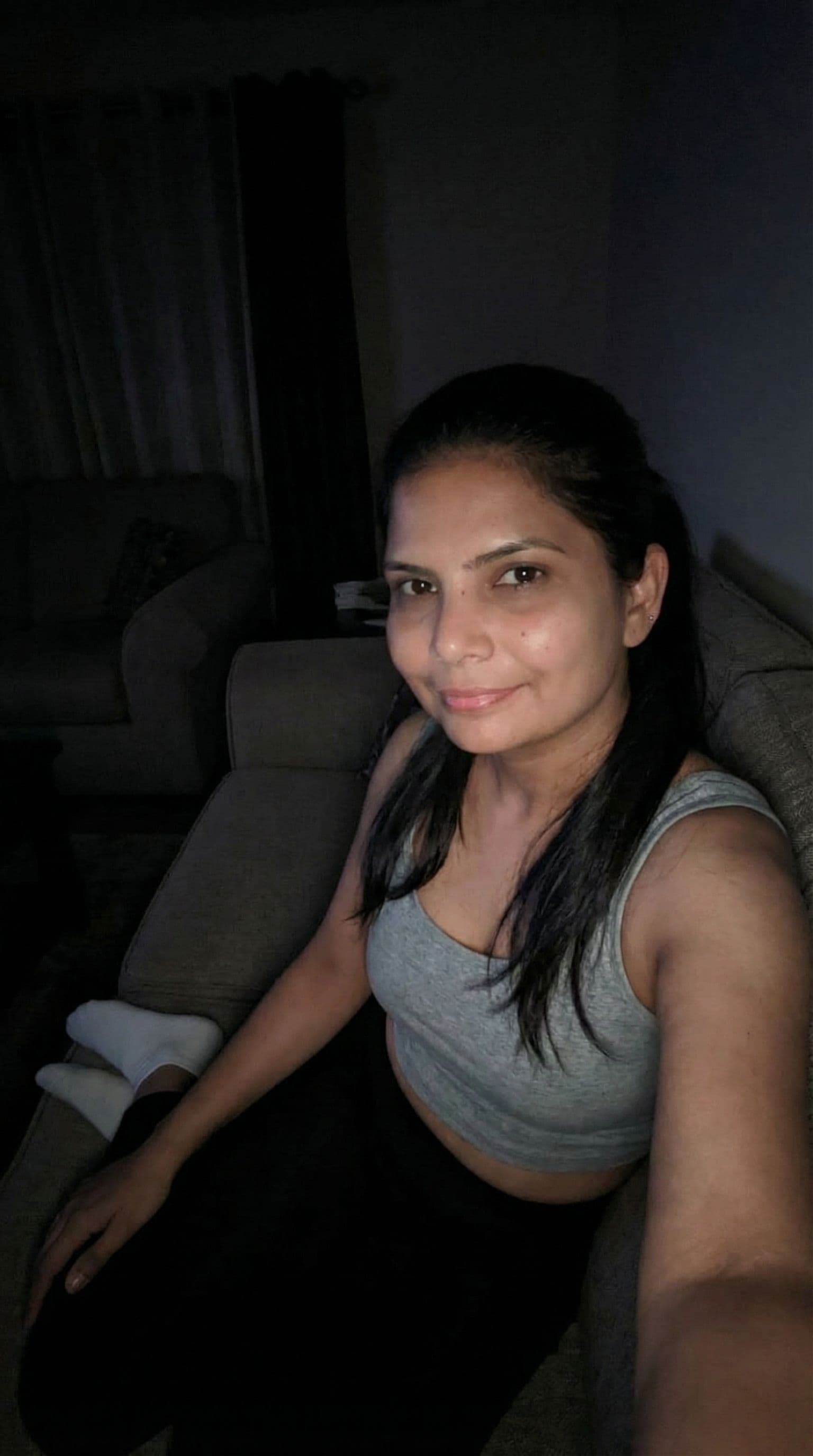 AI generated: Indian, Taking a selfie on a couch at night, no lights, wearing a cropped home tanktop and white soc...