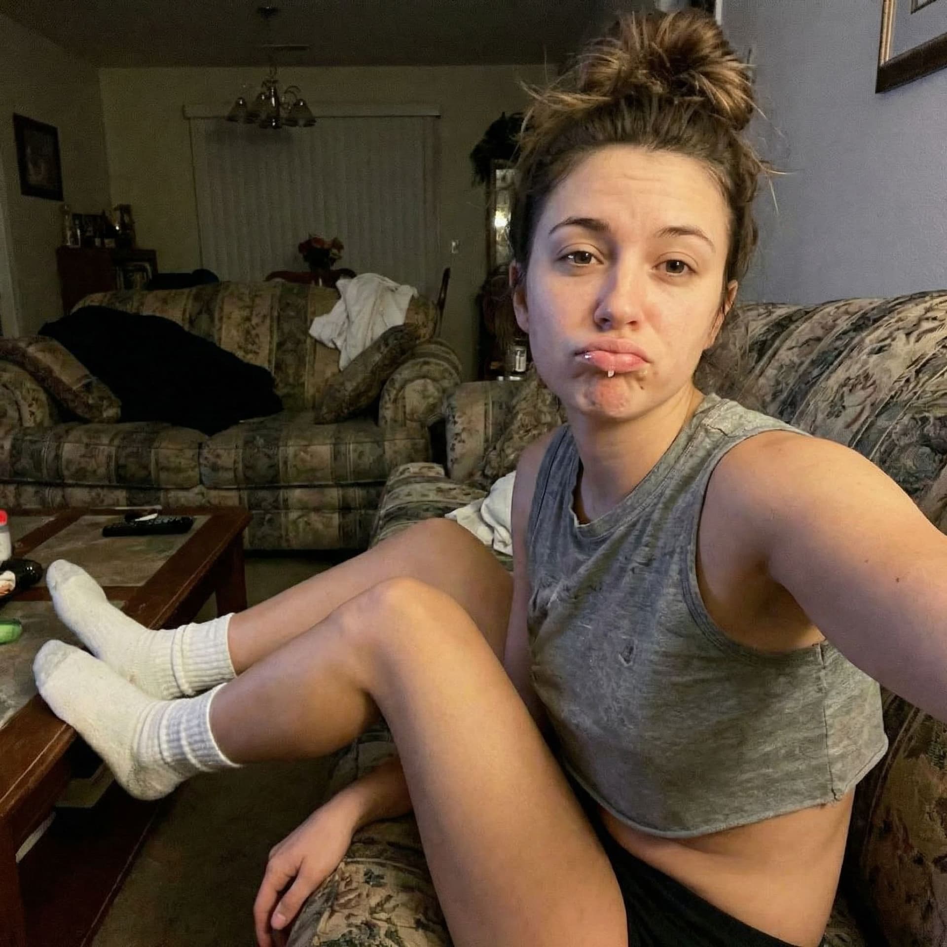 AI generated: Takes a selfie while sitting on a couch, sticking lips out with saliva, wearing a mini cropped tankt...