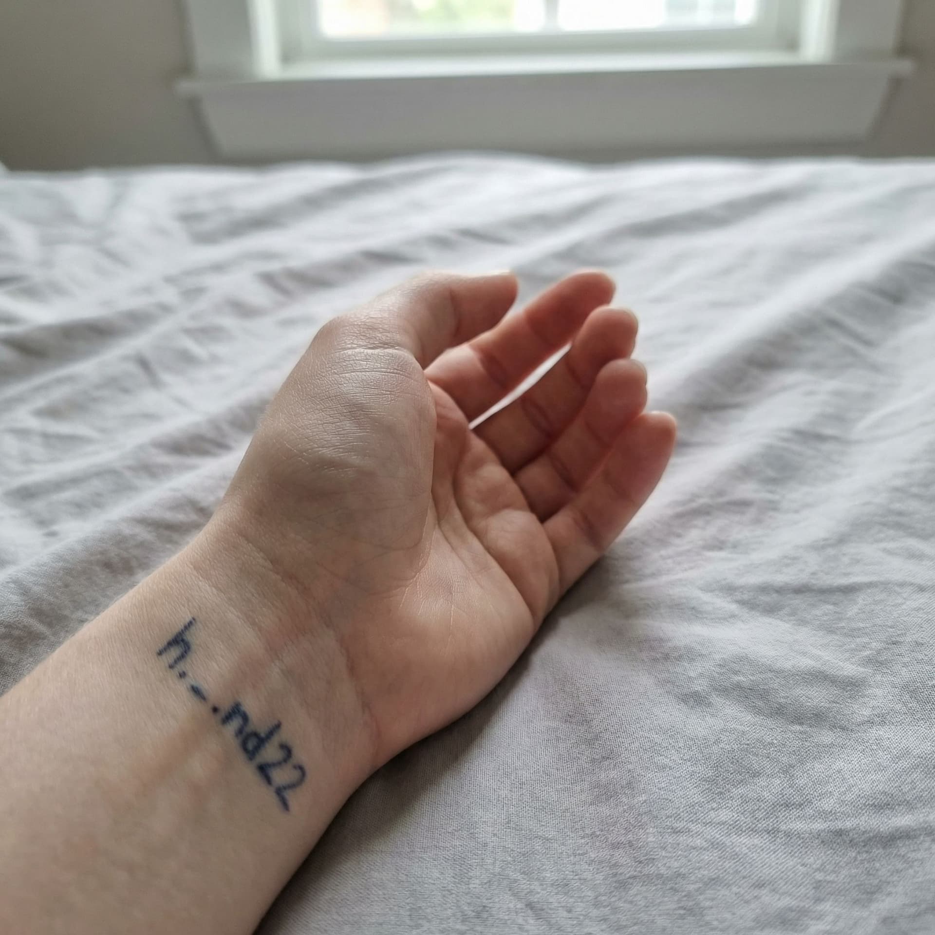 AI generated: Close-up photograph of a 26-year-old woman's hand, pale skin tone, resting on a crumpled bedsheet. O...
