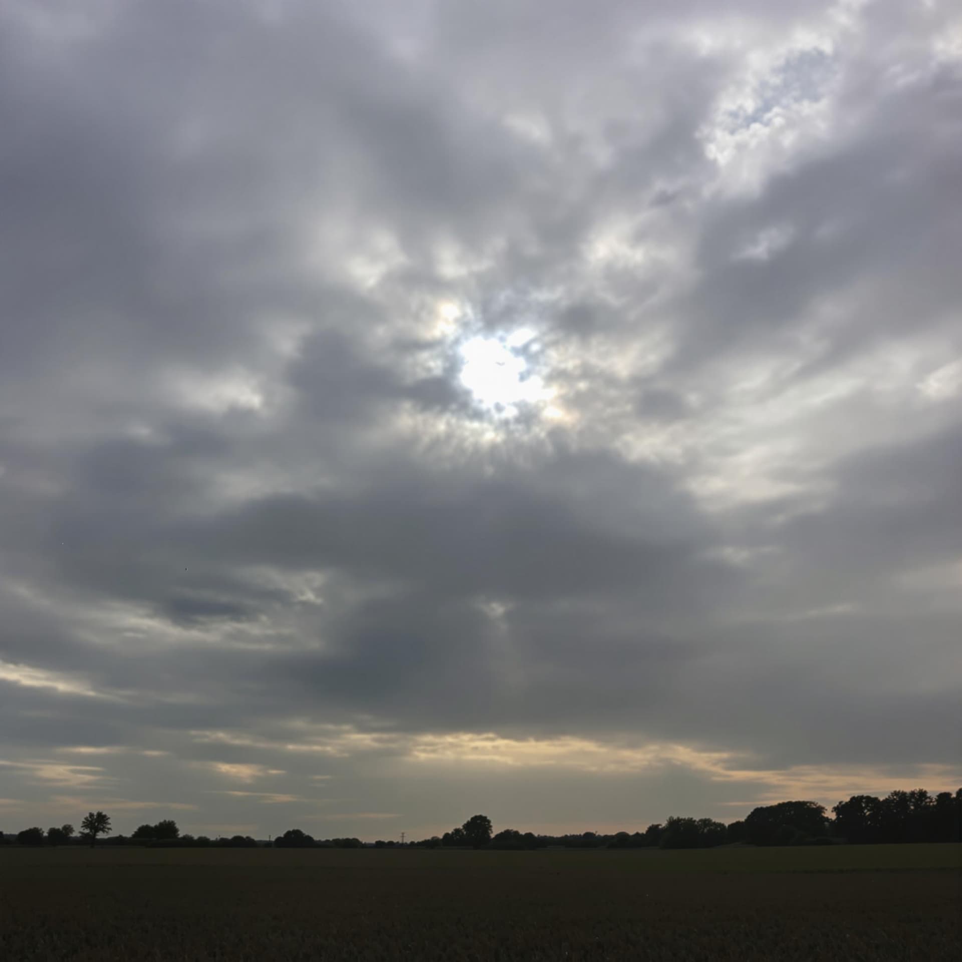AI generated: The horizon above a field, with the sky featuring a darkened and grayish central sun.
