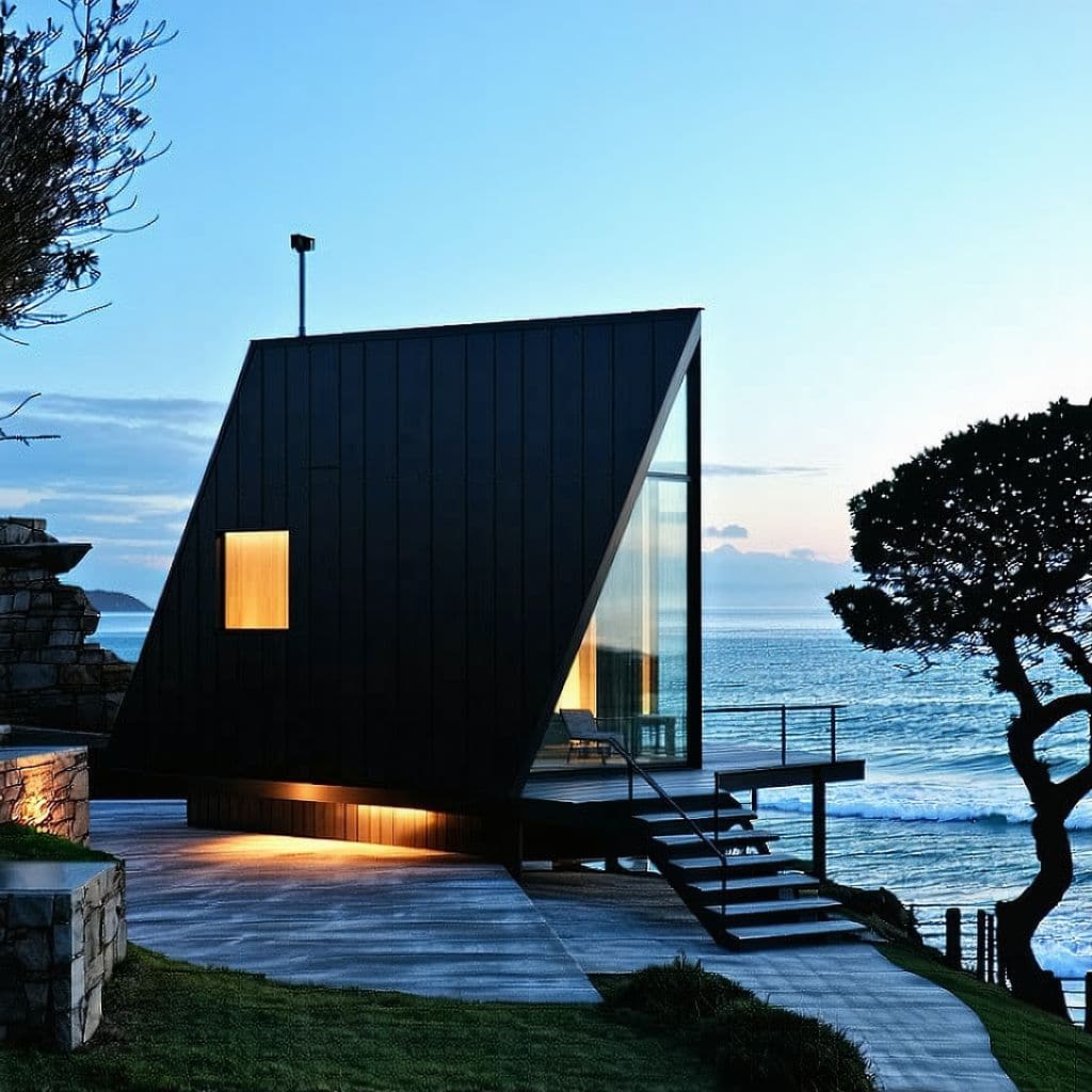 AI generated: modern cabin, tiny house, architecture, minimalist, lights, black steel, concrete, triangle, ocean i...