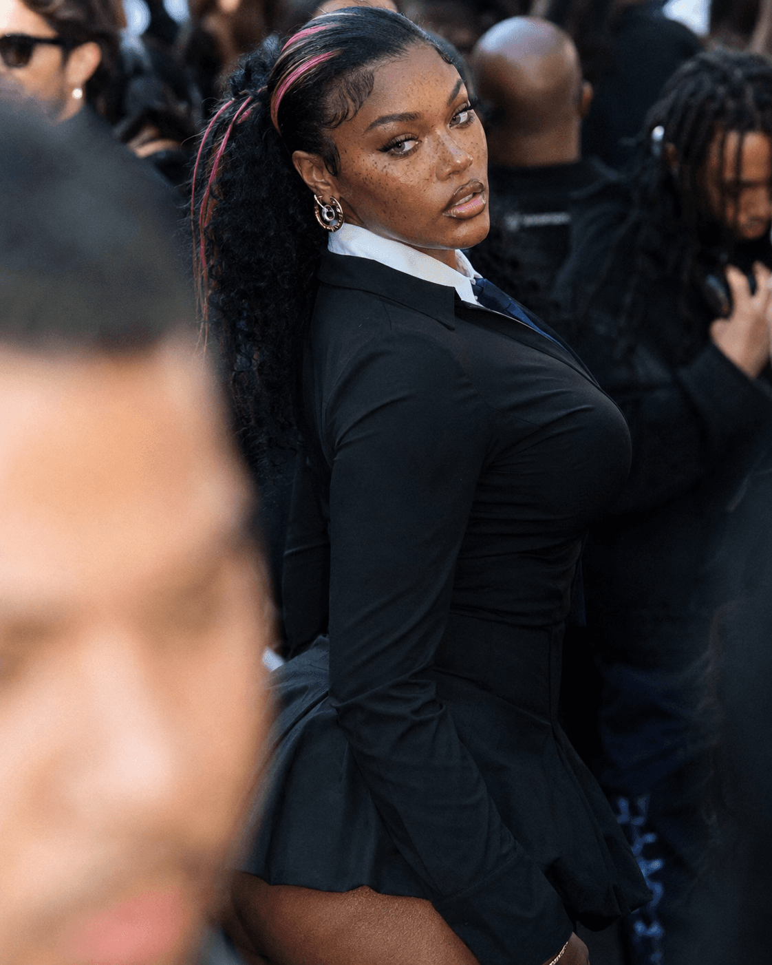 AI generated: candid street-fashion portrait in a dense crowd, subject caught mid-turn while looking back toward t...