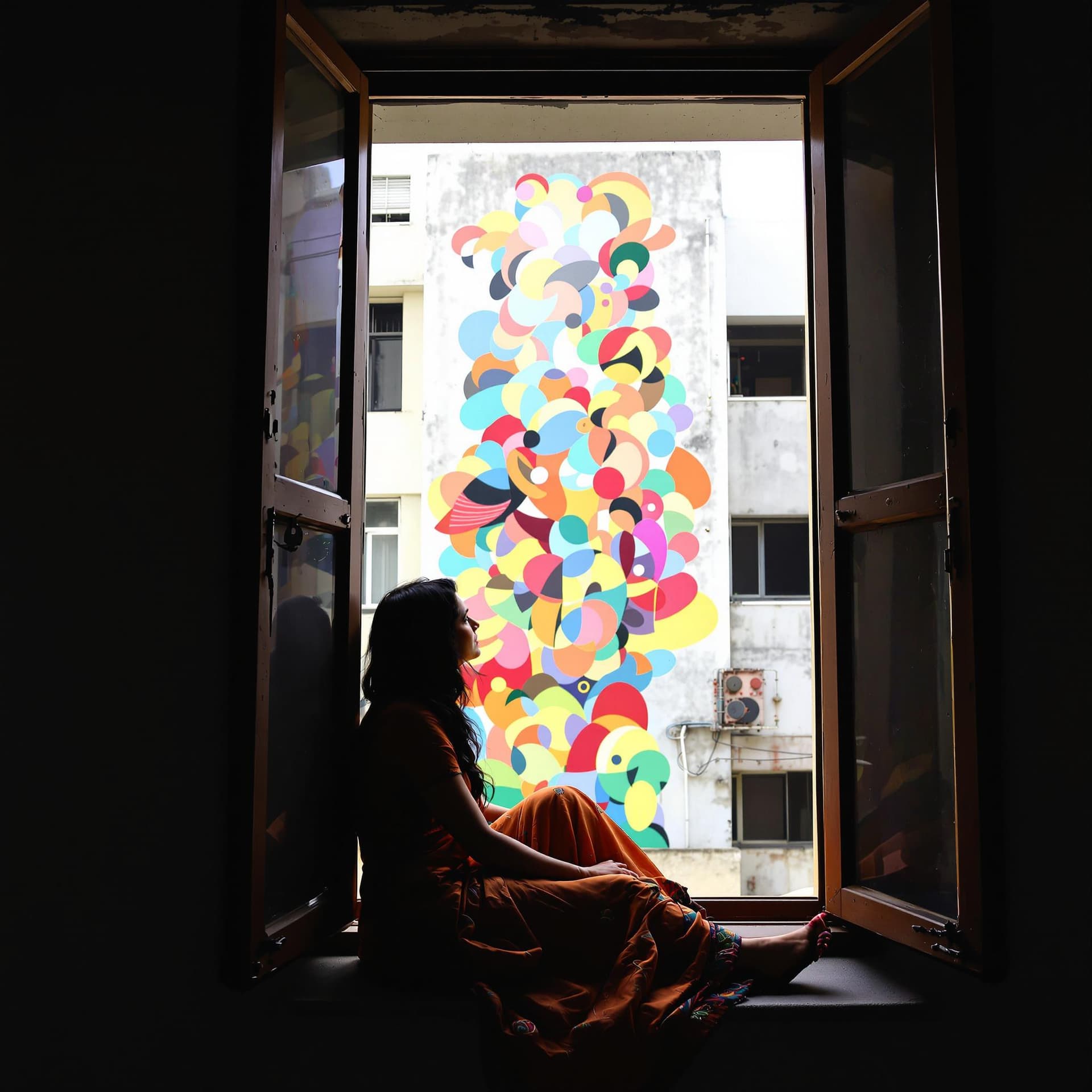 AI generated: a tall open window with a view of a building with a colorful abstract mural, a Indian woman, from th...