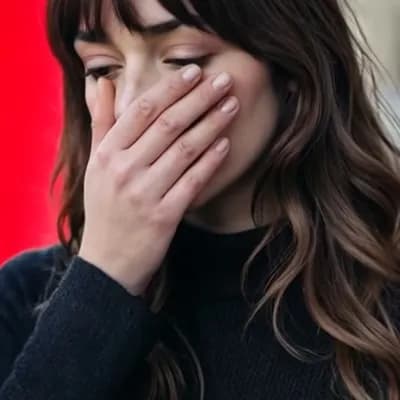 AI generated video: image of a woman with a thoughtful expression, covering half of her face with her hand, pure red bac...